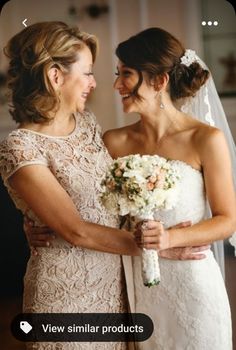 two women standing next to each other in front of a mirror holding bouquets and smiling