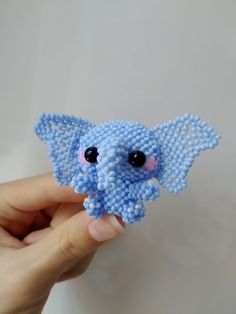 a small blue beaded elephant is held in someone's hand with it's eyes wide open