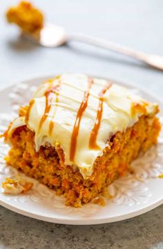 a piece of carrot cake on a plate with a fork and spoon in the background