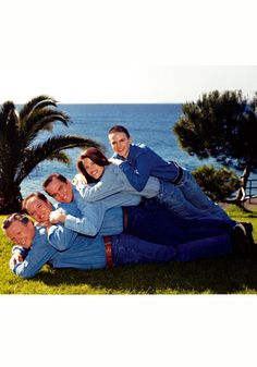 a group of people sitting on top of each other in front of the ocean with palm trees