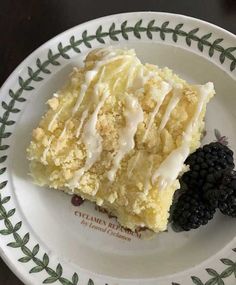 a piece of cake with white icing and blackberries on a green and white plate