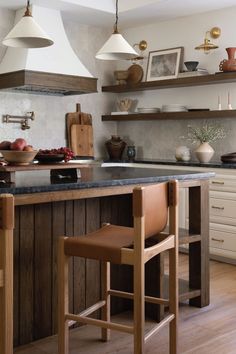 a kitchen island with two stools in front of it and shelves on the wall