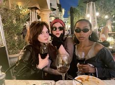 three women sitting at a table with wine glasses