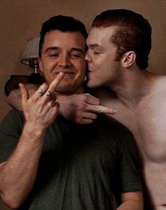 two men kissing each other with their fingers