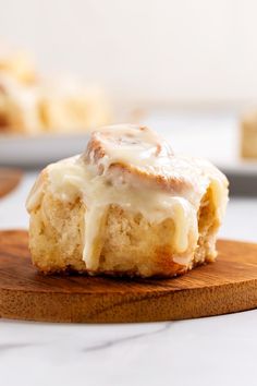 a cinnamon roll with icing sitting on top of a wooden board