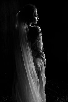 black and white photograph of a woman in a wedding dress with veil over her head