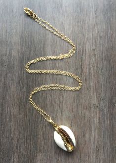 Cowrie Shell Necklace. This real cowrie shell has been dipped in 18k gold. It dangles from a gold-filled chain in your choice of a simple link or satellite chain. Wear it alone or layered for a great boho look. Matching bracelet available: https://www.etsy.com/listing/618535410/cowrie-shell-bracelet-adjustable?ref=shop_home_active_1 Matching earrings available here: https://www.etsy.com/listing/641824355/cowrie-shell-earrings-gold-cowrie-shell?ref=shop_home_active_2 Your cowrie shell necklace wi Boho Necklace Layering, Gold Shell Necklace, Cowrie Shell Necklace, Cowry Shell, Necklace Layering, Myrtle Beach Sc, Shell Bracelet, Matching Bracelet, Shell Necklace