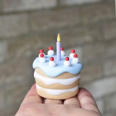 a hand holding a small cupcake with candles on it