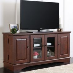 a flat screen tv sitting on top of a wooden entertainment center in a living room