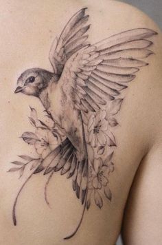 a bird tattoo on the back of a woman's shoulder