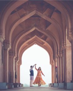 two people standing in an archway with one holding the other's hand and dancing