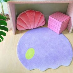 a pink and purple rug sitting on top of a wooden floor next to a green plant