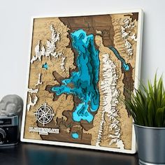 a wooden map of lake tahoe is shown on a table next to a potted plant