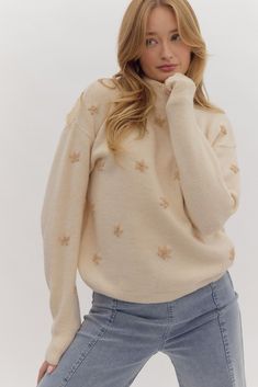 a woman is posing with her hand on her chin and wearing a white star sweater