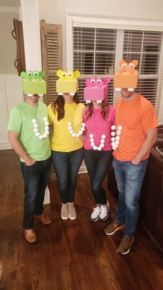 four people wearing silly hats and necklaces in a living room with wood floors, windows and shutters