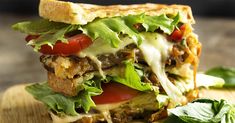 a cut in half sandwich sitting on top of a cutting board next to some leaves