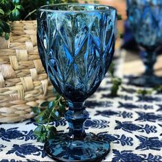 a blue glass sitting on top of a table next to a basket filled with flowers