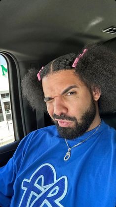 a man sitting in the back seat of a car with an afro on his head