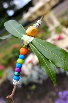 a colorful beaded necklace hanging from a tree branch