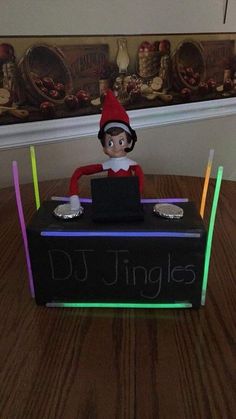 an elf is sitting on top of a dj's box with neon sticks around it