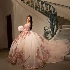 a woman in a ball gown standing next to a stair case and staircase railings