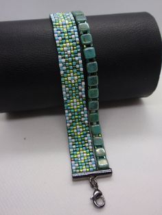 two bracelets are sitting on top of a black leather case and one is made out of glass beads