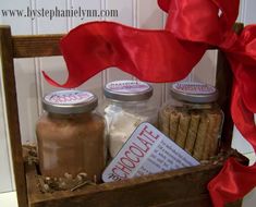 a wooden box filled with spices and cinnamons next to a red ribbon on a white wall