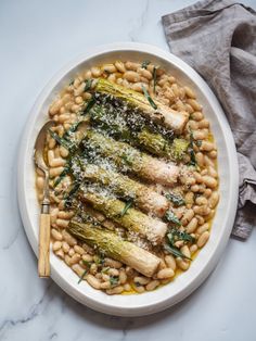 a white plate topped with beans and asparagus covered in parmesan cheese