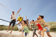 group of people playing volleyball on the beach