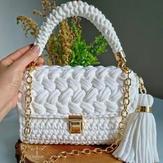 a woman holding a white purse on top of a table