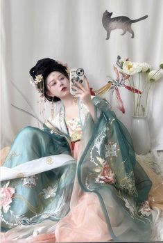 For the spring fairy, this gorgeous Tang Dynasty inspired set is adorned head to toe with embroideries of lotuses, mandalas and peacock feathers. Not one corner is neglected! From the wrists to the back, envelop yourself in the luxuries of high quality flowers. The Daxiushan (大袖衫, wide sleeved jacket) is dramatic and elegant, creating movement and grace with its exaggerated sleeves. Layer the embroidered jacket over the sheer jacket for a dimensional effect. The star of the show is the Heziqun ( Spring Wedding Green Kimono, Traditional Spring Wedding Kimono, Spring Wedding Kimono With Floral Embroidery, Lotus Fairy, Modern Hanfu, Spring Fairy, History Taking, Sheer Jacket, Exaggerated Sleeves