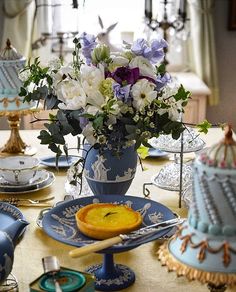 a table topped with blue and white plates covered in cake next to a vase filled with flowers