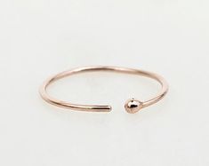 a rose gold ring with a tiny ball on the middle and a small bead at the end