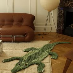 a crocheted alligator rug on the floor in front of a couch and chair