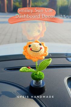 a small crocheted sun car dashboard decoration with a smiling face on it's head