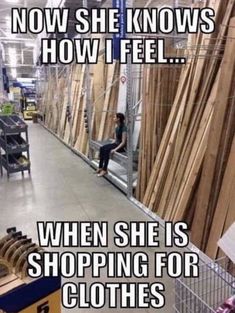 a woman is sitting on the edge of a shopping cart and looking at wood planks