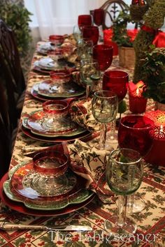 the table is set with red glassware and place settings