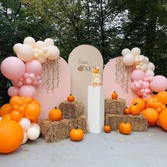 an orange and white cake surrounded by hay bales, pumpkins and balloon decorations