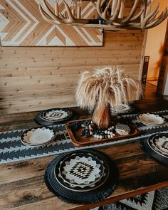 the table is set with black and white plates, an antler's head on top