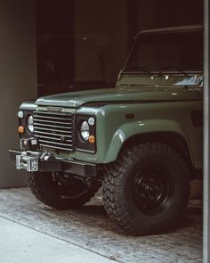 a green land rover is parked in front of a building