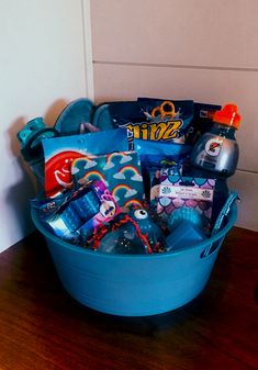 a blue bucket filled with lots of items on top of a wooden table next to a wall