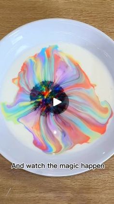 a white plate topped with a colorful flower on top of a wooden table