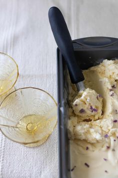 ice cream in a pan with two glasses next to it on a white tablecloth