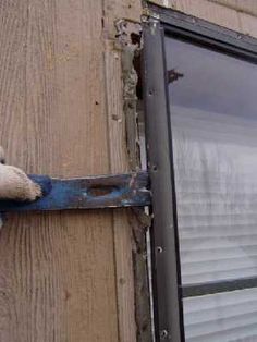 a teddy bear hanging on the side of a wooden wall with a window in it