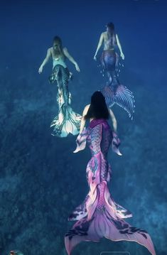 two mermaids are floating in the water