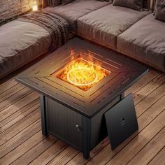 a fire pit sitting on top of a wooden floor next to a couch and pillows