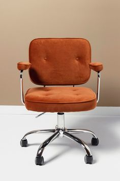 an orange office chair sitting on top of a white table