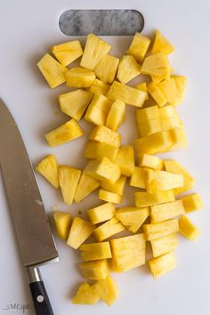 cut up pieces of pineapple sitting on top of a cutting board next to a knife