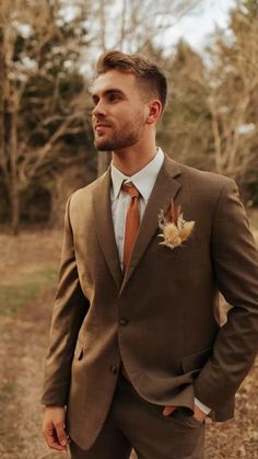 a man wearing a suit and tie standing in the woods