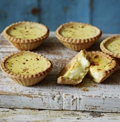 four small pies sitting on top of a wooden table with one cut in half